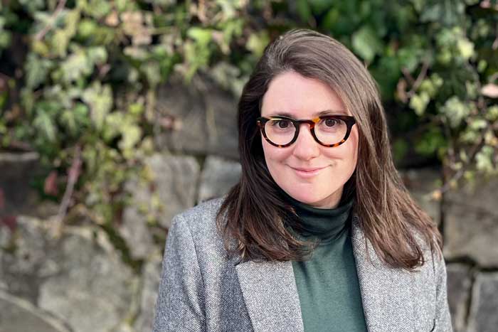 Portrait of Chloe Wittenberg wearing a jacket over a turtleneck and standing outdoors