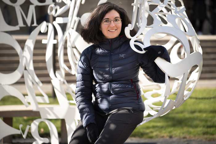 Tamara Broderick sits on The Alchemist sculpture on campus