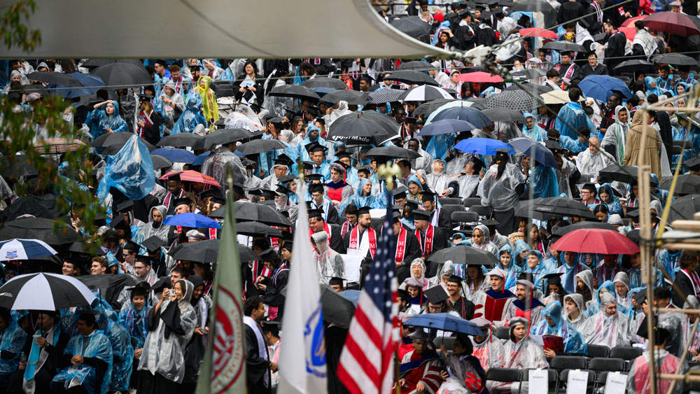 A crowd of graduates and guests holding umbrellas at MIT's Commencement