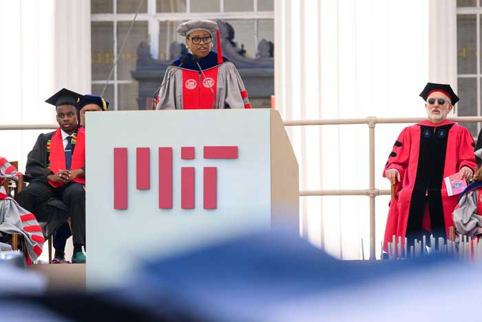 Nobles speaks at the podium to the audience while wearing regalia