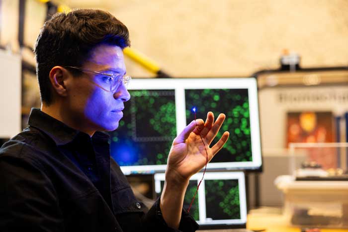 Guillermo Herrera-Arcos looks at blue light shining from an optical neurostimulator