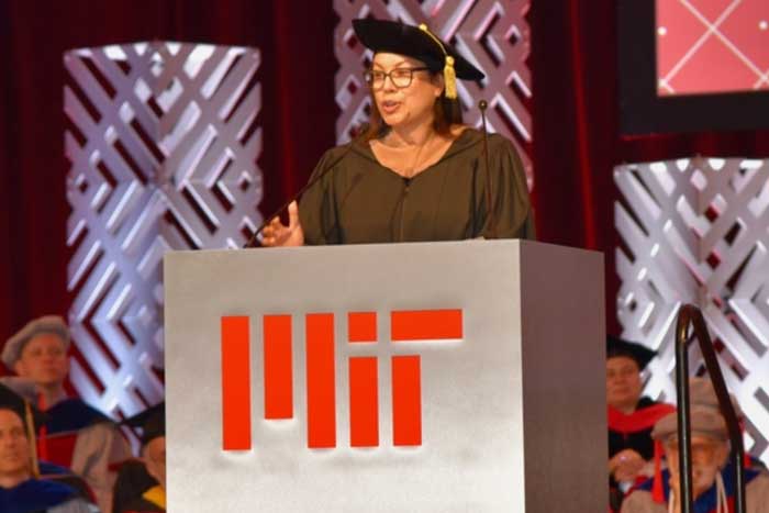 Diane Hoskins speaks at a podium during an indoor graduation ceremony