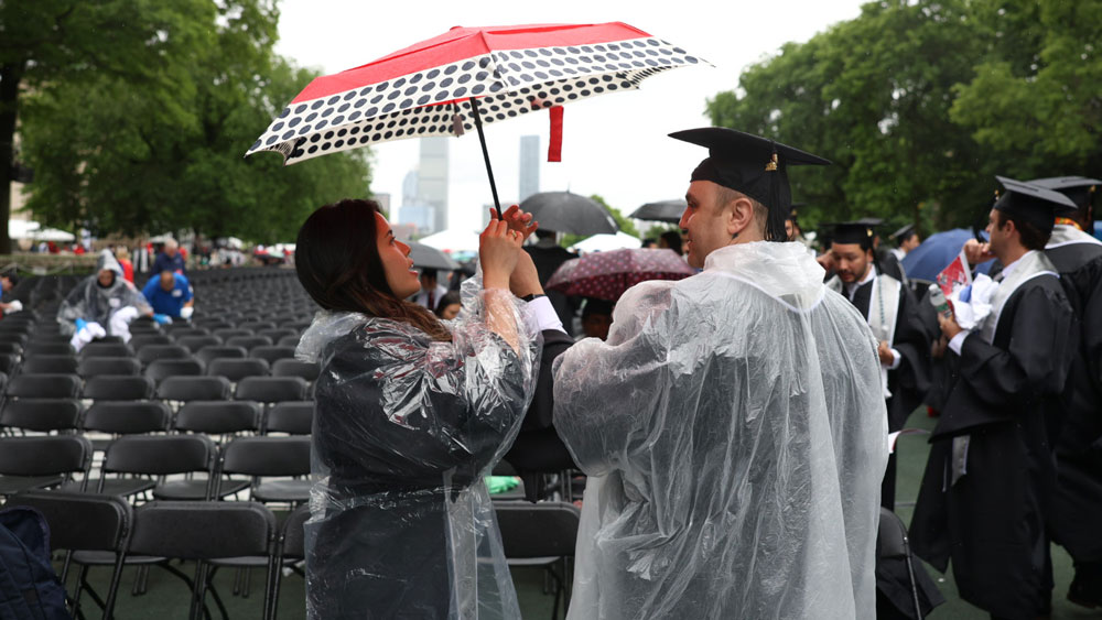 MIT graduates under an umbrella on MIT's Killian Court