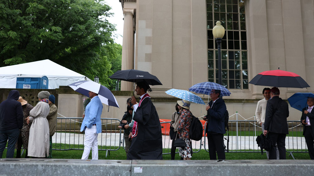 a line of Commencement attendees standing with umbrellas