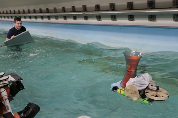 A person in a water tank observes a floating prototype.