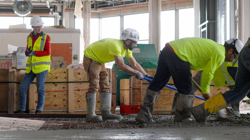 Workers smooth out wet cement indoors