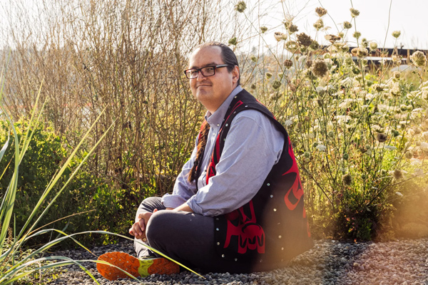 Anthony Jones sits outside on the ground with grasses