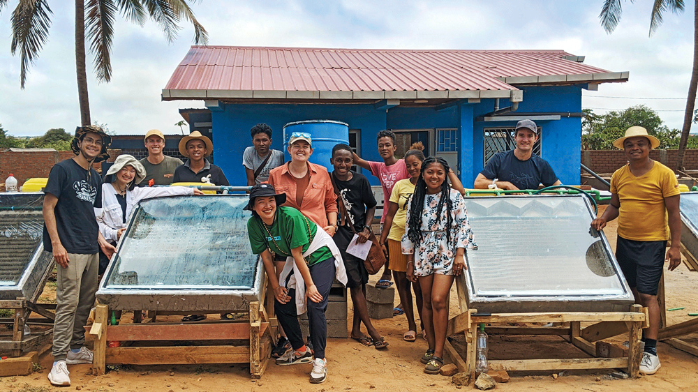 About 15 people pose for a photo around two small desalination systems in Madagascar