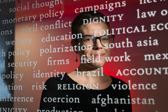 Ariel White portrait behind a window with frosted words printed on it, like “Dignity; polarization; conflict.”