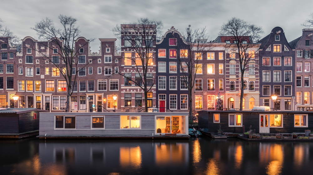 a row of houses with lights on located on a canal in Amsterdam