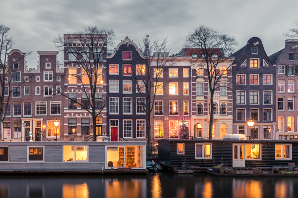 a row of houses with lights on located on a canal in Amsterdam