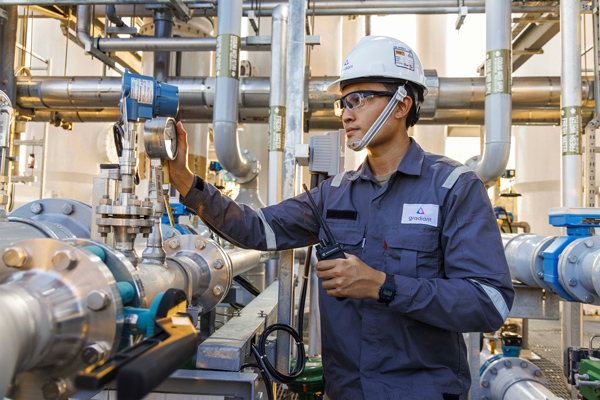 Person in hardhat inspects thermometer in factory