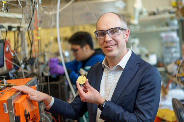 Zachary Smith holds a coin-like object in the lab.