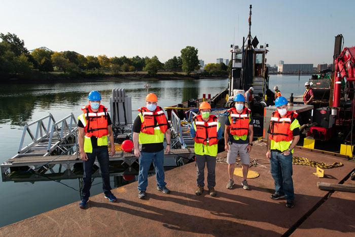 5 people in orange vests near a dock and water craft