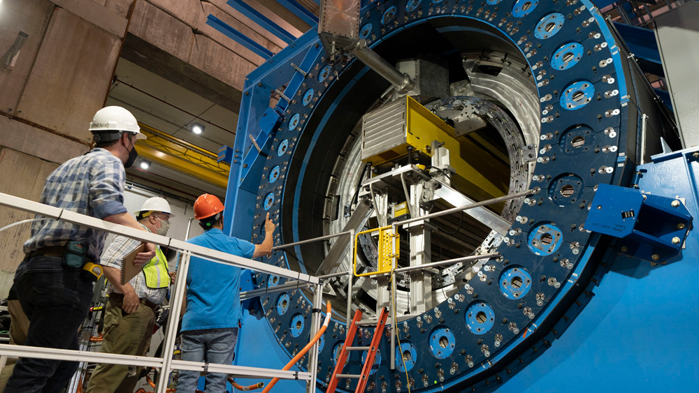 three workers looking into a particle detector