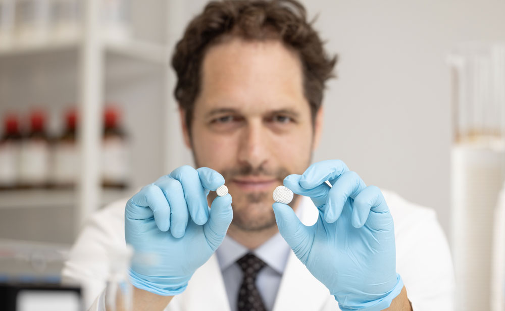 Aron Blaesi holds two pills, one smaller than the other