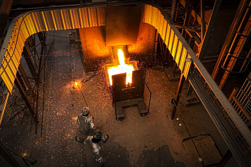 2 Steel factory workers observe pouring molten steel