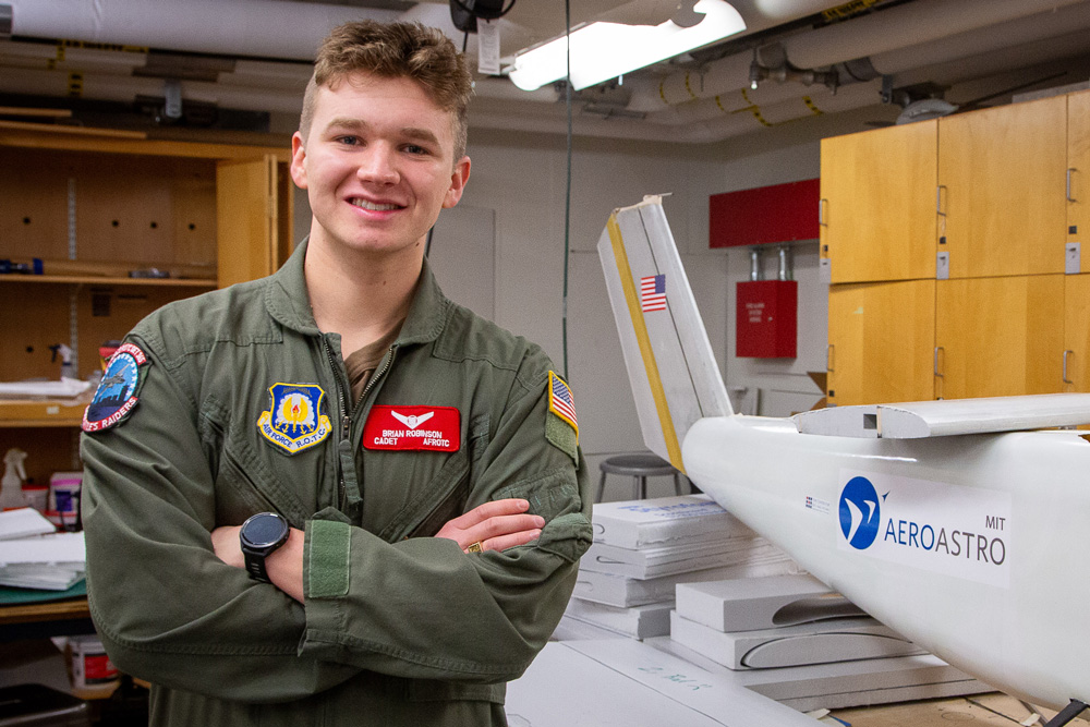 Brian Robinson wears an AFROTC jacket and next to a model of an airplane