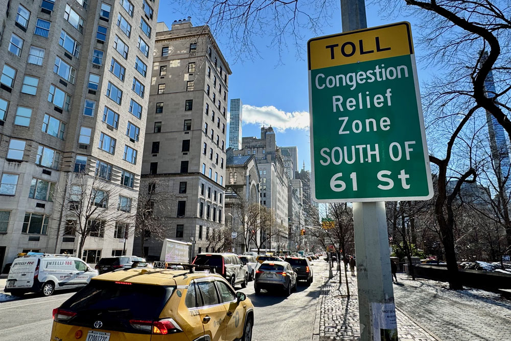 A sign on a busy NYC street says "Toll; congestion relief zone south of 61st"