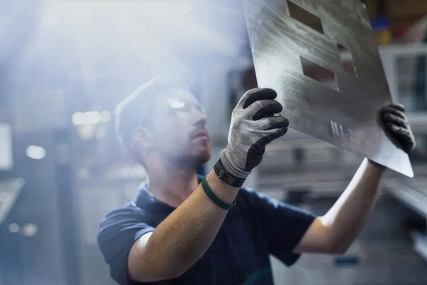 a worker examining a a sheet of metal
