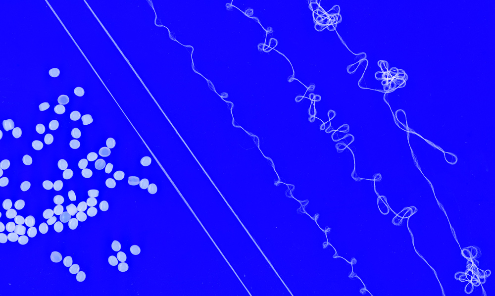 On blue background, plastic pellets (left) become yarn strands (right)
