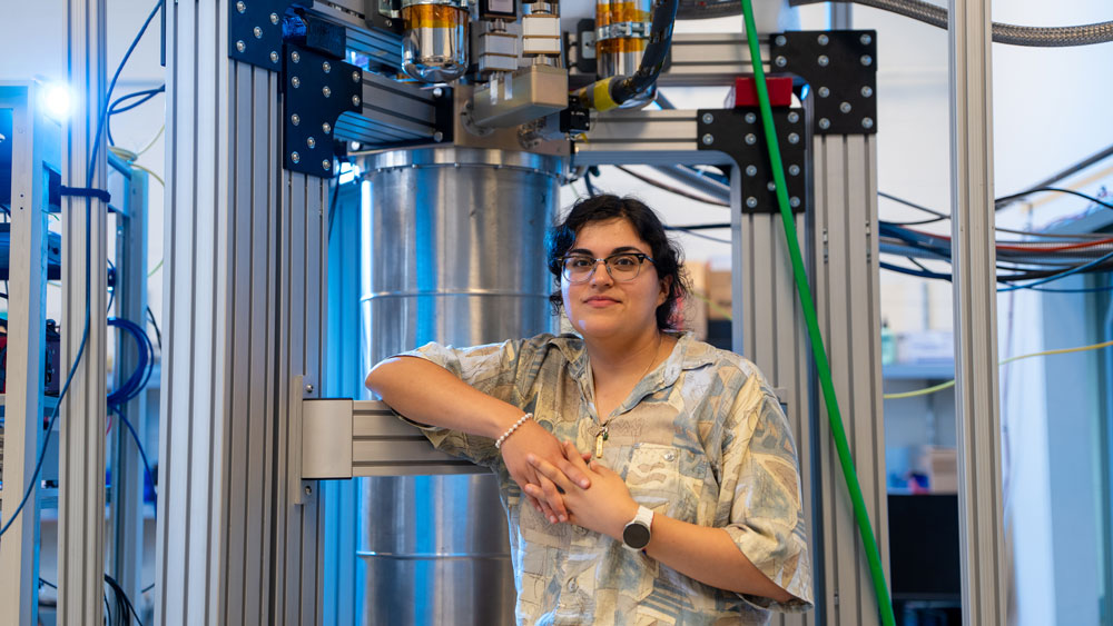 Faith Reyes leans on a large machine in the lab