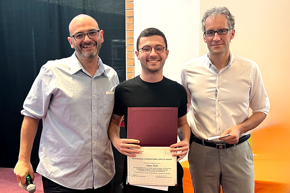 Angus Wylie in the center holding an award certificte with Matteo Buccito the left and Jacopo Buongiorno to the right, in a row, MIT