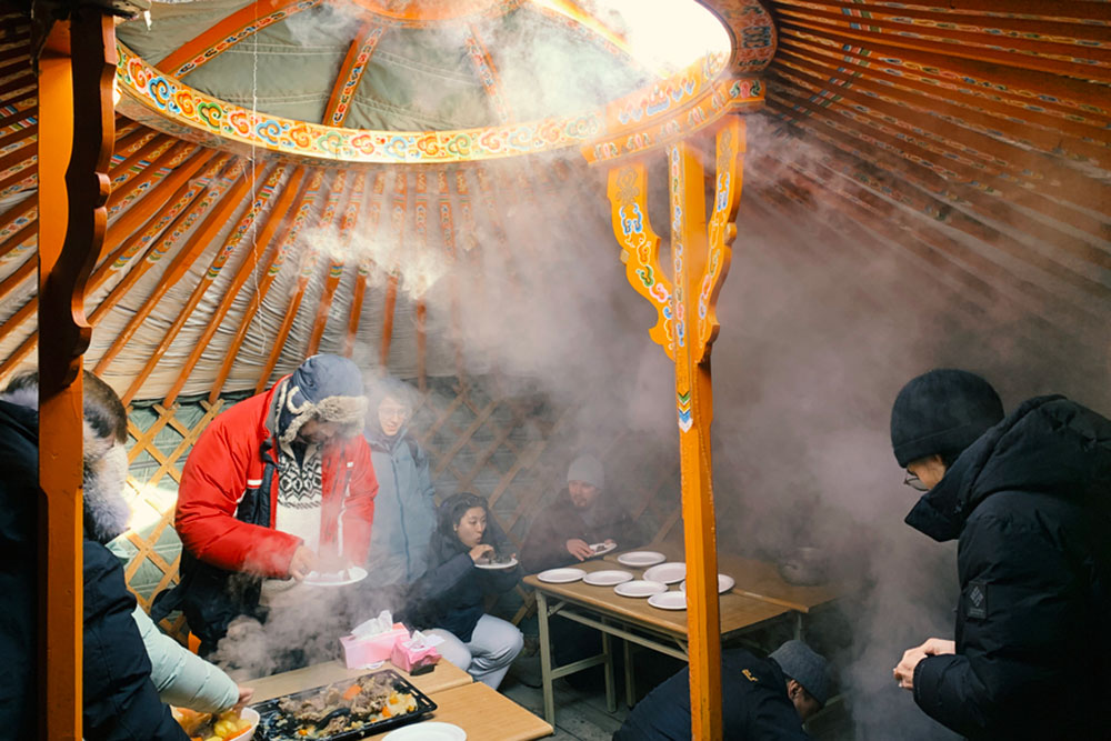 Seven people inside a traditional ger dwelling gathered for a khorkhog cookout