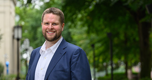 Headshot of faculty member Ethan Peterson, outdoors against a green trees, MIT