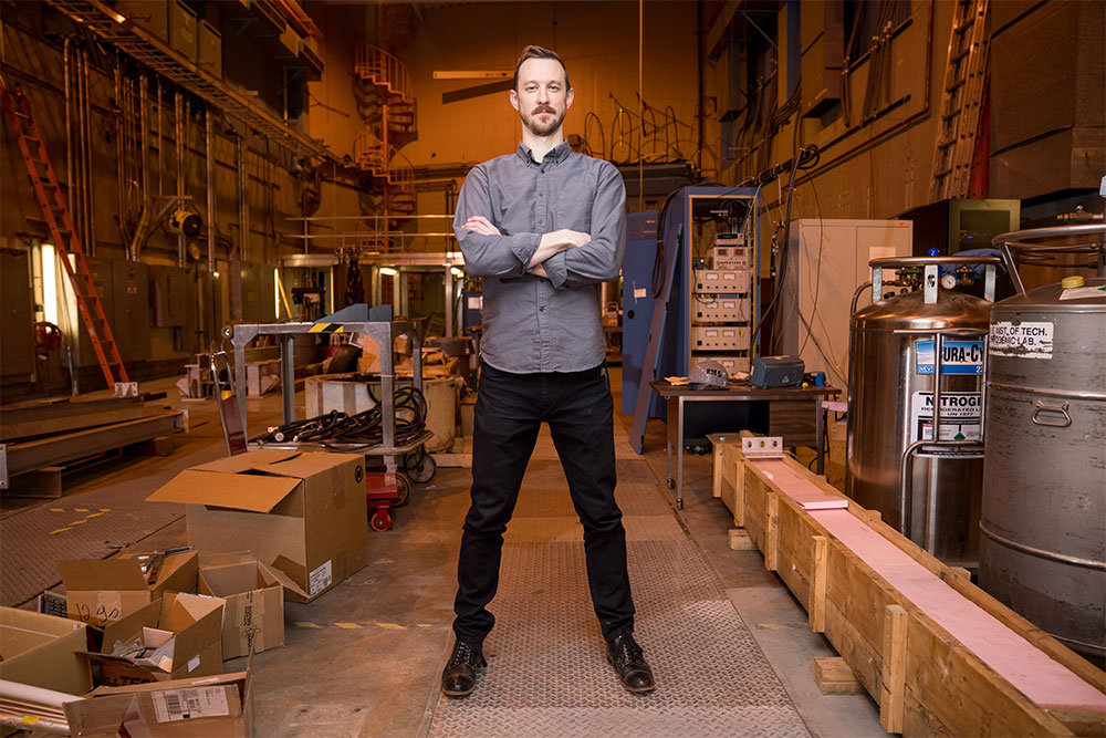 Faculty member Zachary Hartwig stands arms folded inside a lab space at MIT