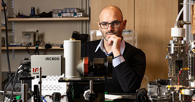 Faculty member Matteo Bucci seated at a lab bench with instruments, MIT