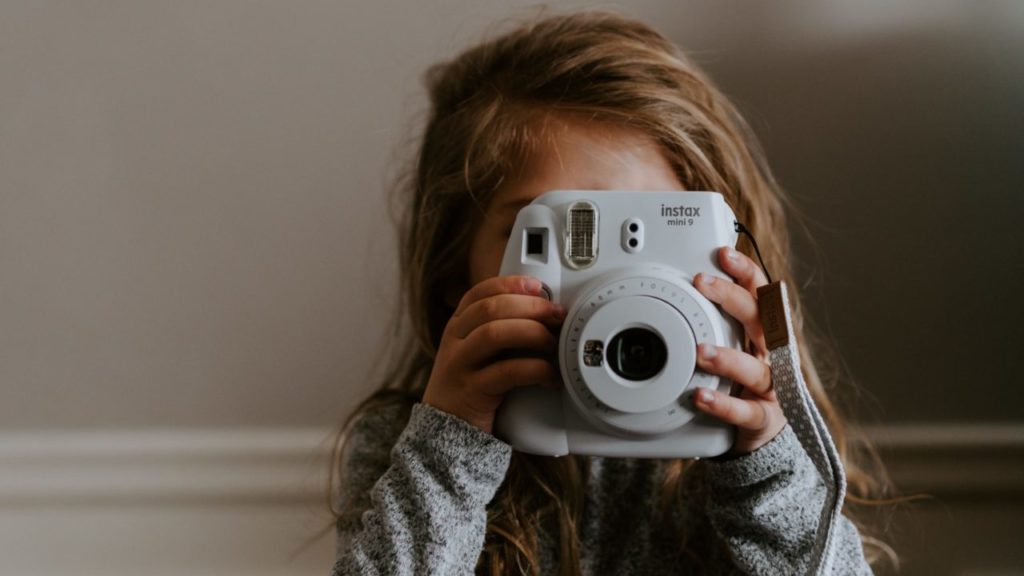 girl taking a picture using instant camera